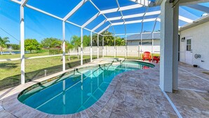 A covered swimming pool with a clear blue water feature, surrounded by a white metal frame structure.