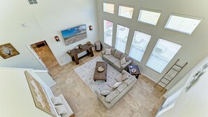 A spacious living room with a large window, a sofa, a coffee table, and a painting on the wall.