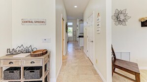 A hallway with a sign reading "CENTRAL SPRAWL," a wooden bench, and a decorative wall piece.