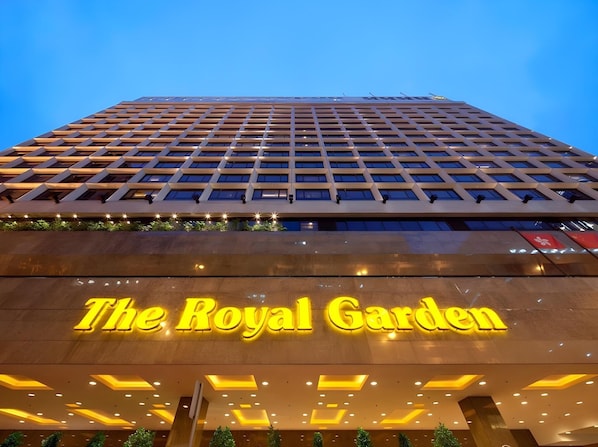 De gevel van het Royal Garden hotel met een raster van ramen en een opvallend verlicht bord.