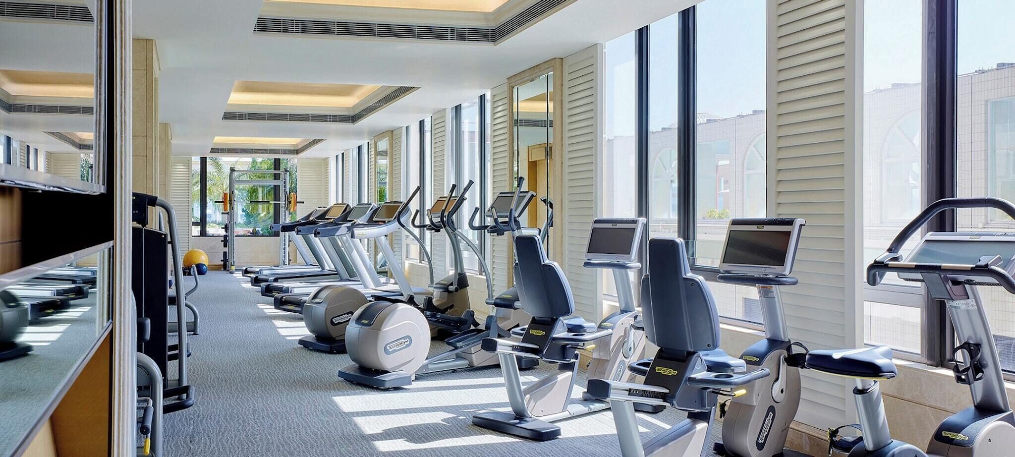 Un gimnasio con cintas de correr, elípticas y bicicletas estáticas.