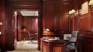 Een zakelijke werkkamer met een houten bureau, een stoel en een lamp.