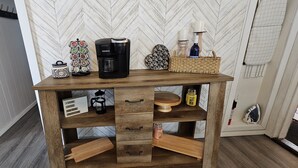 A wooden coffee table with a coffee maker, a candle holder, and a basket.
