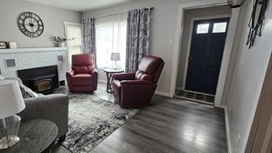 A living room with a fireplace, two leather chairs, a coffee table, and a rug.