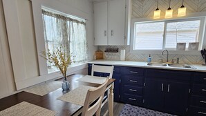 A modern kitchen with dark blue cabinets, a white countertop, and a window with blinds.