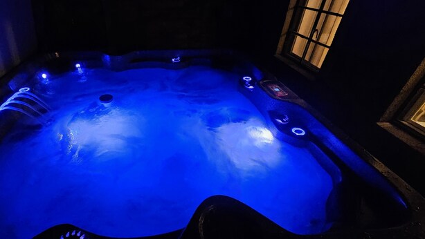 A hot tub with a blue light, a control panel, and a window.