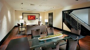 A modern conference room with glass tables, comfortable seating, a large painting on the wall, and a staircase. - Walkable, Pet friendly FIDI 1BR w/ Sauna & Rooftop Deck (New York)