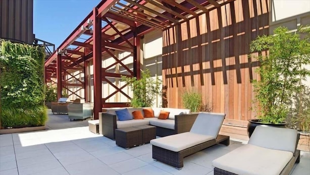 An outdoor patio area with a sofa set, a lounge chair, and a pergola structure. - Walkable, Pet friendly FIDI 1BR w/ Sauna & Rooftop Deck (New York)