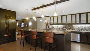 A modern kitchen with dark cabinetry, a marble countertop, and pendant lighting. - Walkable, Pet friendly FIDI 1BR w/ Sauna & Rooftop Deck (New York)
