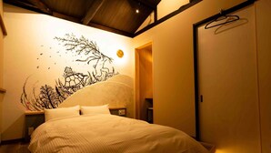 Une chambre à coucher comprenant un lit, une peinture murale, une armoire et un luminaire suspendu.
