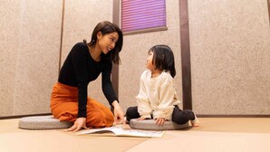 Une pièce avec des tatamis, un coussin de tatami et une fenêtre avec des stores.