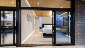 A modern bedroom with a large bed, a nightstand, and a wall-mounted light. - Modern Scottsdale Villa Walk to Old Town , 4BR Pool & Spa (Scottsdale)