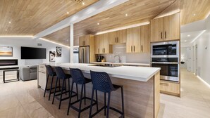 A modern kitchen with a central island, bar stools, wooden cabinets, and built-in appliances. - Modern Scottsdale Villa Walk to Old Town , 4BR Pool & Spa (Scottsdale)