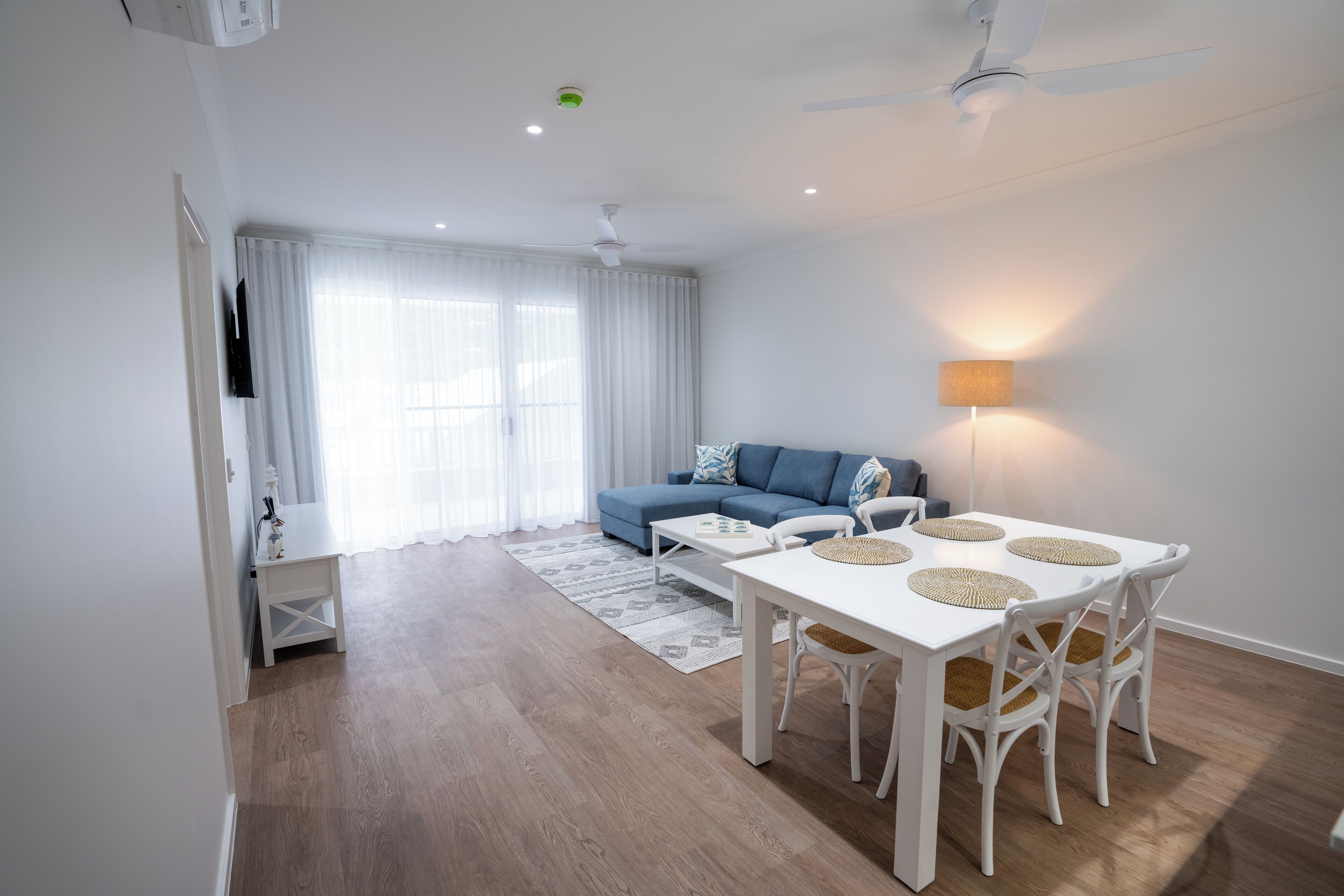 Un salon moderne avec une table à manger, un canapé et un ventilateur de plafond.