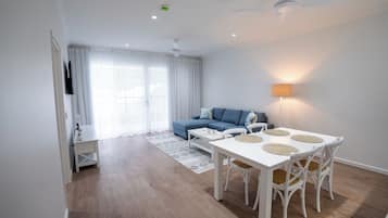 Un salon moderne avec une table à manger, un canapé et un ventilateur de plafond.