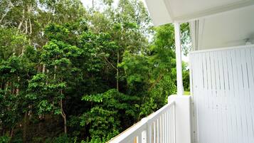A balcony with a white railing overlooking a dense forest.