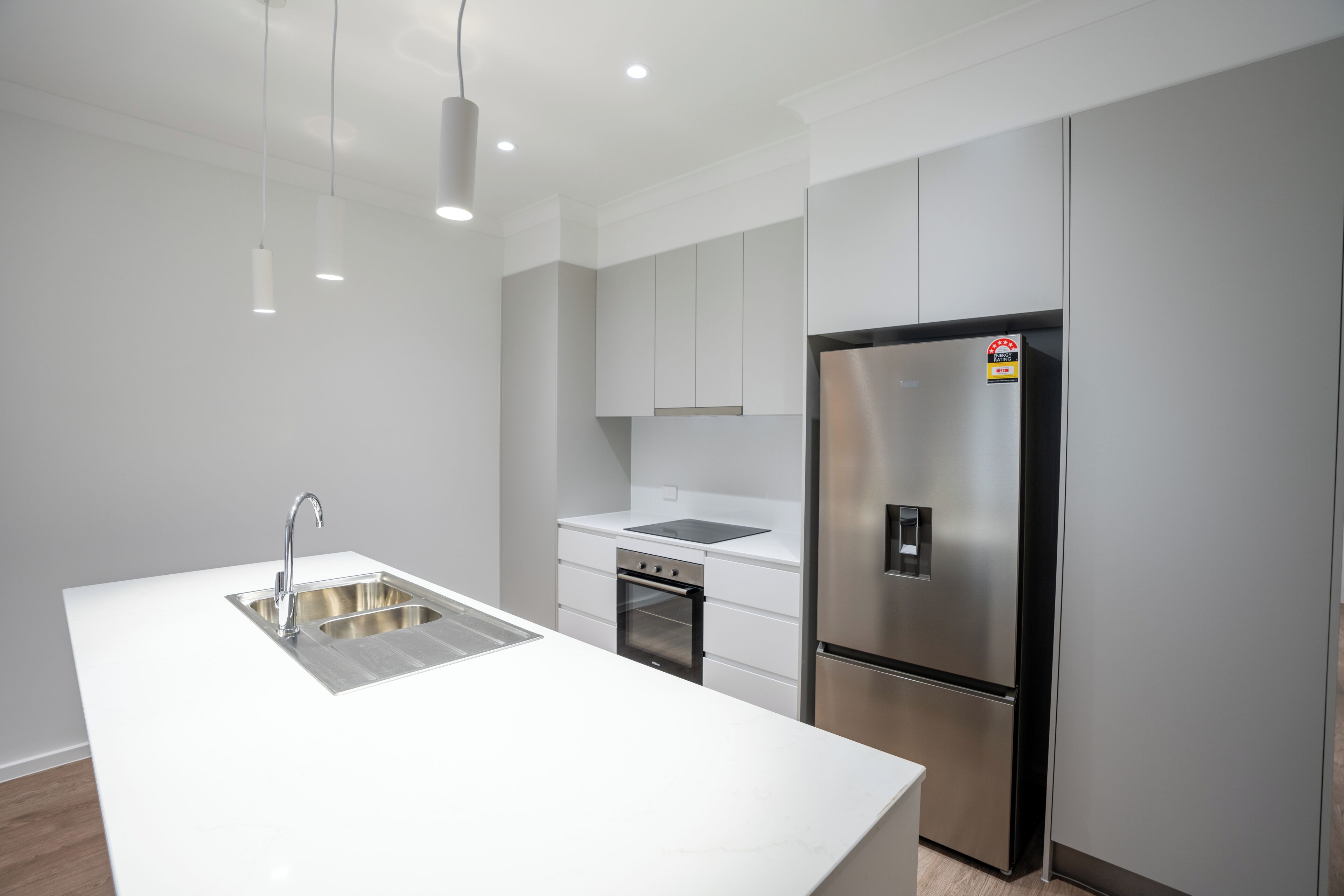 A modern kitchen with a stainless steel refrigerator, a double sink, and a built-in oven.