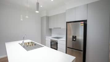 A modern kitchen with a stainless steel refrigerator, a double sink, and a built-in oven.
