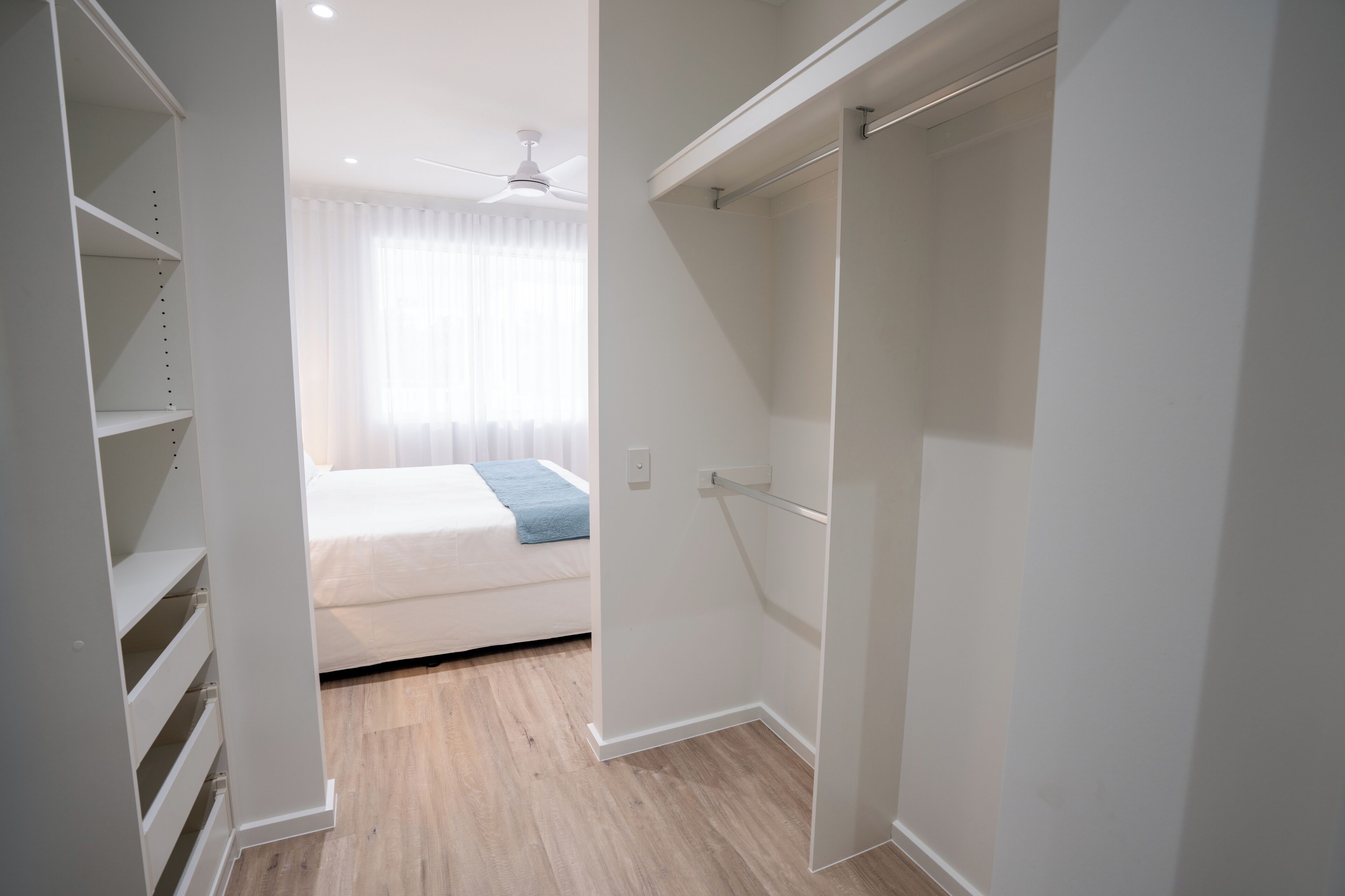 Un dormitorio con cama, armario y ventana con cortinas.