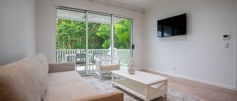 A modern living room with a sofa, a coffee table, and a TV mounted on the wall.