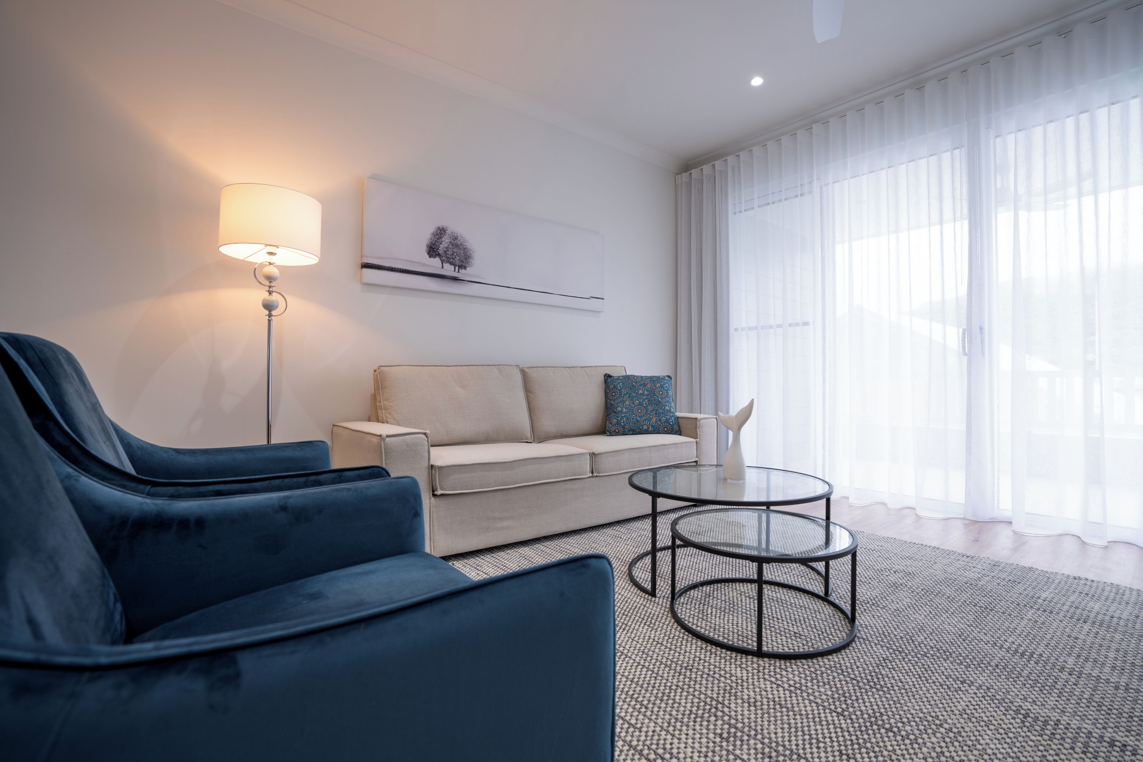 A modern living room with a sofa, two armchairs, a coffee table, and a floor lamp.