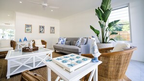 Ein modernes Wohnzimmer mit einer Couch, einem Couchtisch und einer großen Topfpflanze.