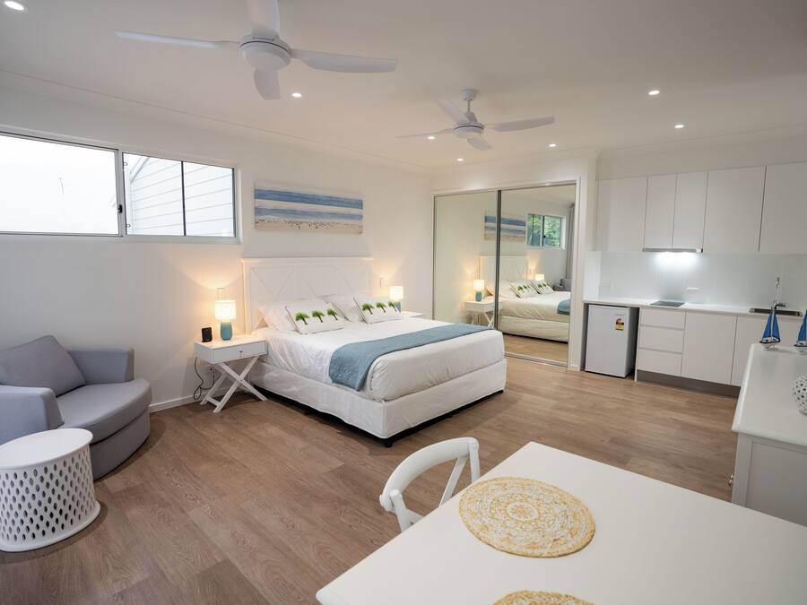 Un dormitorio moderno con una cama, mesitas de noche, una pequeña mesa redonda y un sofá.