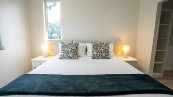 A neatly made bed with a dark throw blanket, two matching pillows, and two bedside lamps.