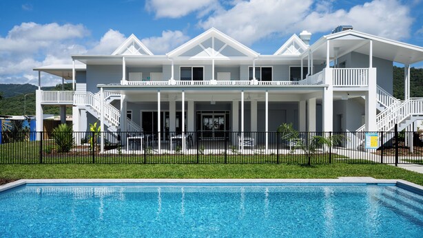 Ein gro ßes, weißes, zweistöckiges Haus mit einem Pool davor.