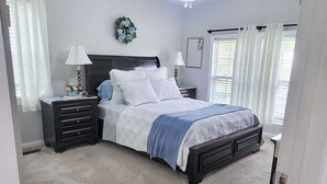 A bedroom with a bed, nightstands, a dresser, and a chandelier. - Amazing Women’s and Men’s Masters Tournament Rental- Fully Remodeled. (Martinez)