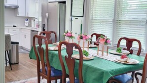 A dining area with a green tablecloth, wooden chairs, and a floral centerpiece. - Amazing Women’s and Men’s Masters Tournament Rental- Fully Remodeled. (Martinez)