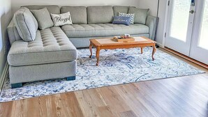 A living room with a sectional sofa, a wooden coffee table, and a patterned rug. - Amazing Women’s and Men’s Masters Tournament Rental- Fully Remodeled. (Martinez)