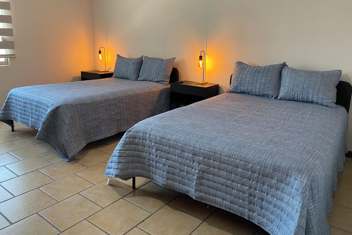 Two twin beds with matching bedding, bedside lamps, and a tiled floor.