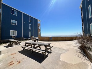 A building with a blue exterior, a wooden fence, and a picnic table in the foreground.