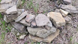 Un foyer en pierre, entouré d’herbe et de rochers.