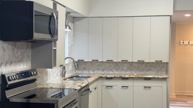 A modern kitchen with a built-in oven, microwave, and stainless steel sink.