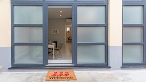 A modern building entrance with large glass doors, a dining area visible inside, and a welcome mat outside. - Champagne Loft (Milan)