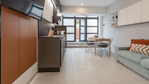 A modern kitchen with a central island, a dining area with a table and chairs, and a light green sofa with a patterned cushion. - Champagne Loft (Milan)