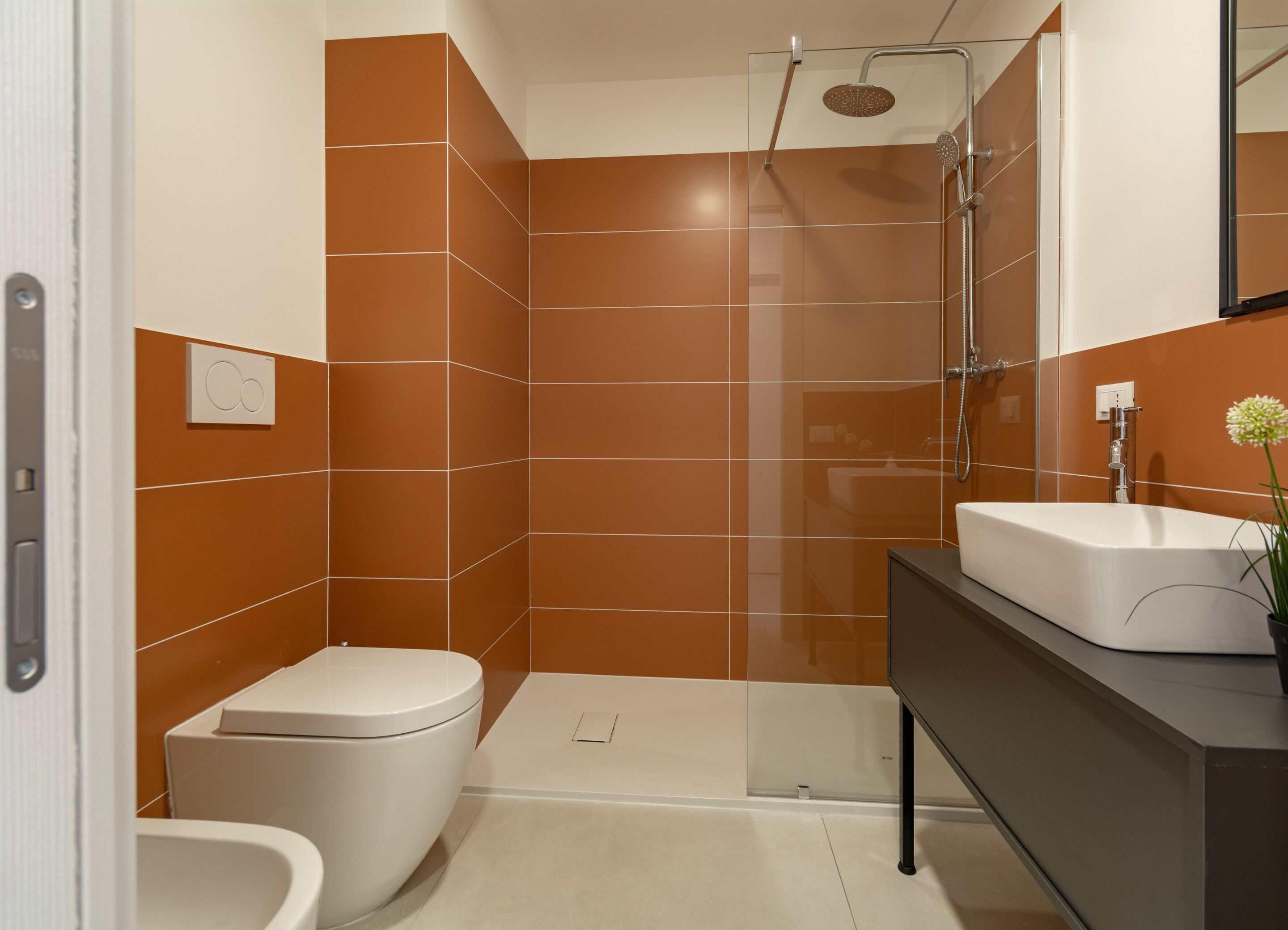 A modern bathroom with a shower, toilet, and sink.