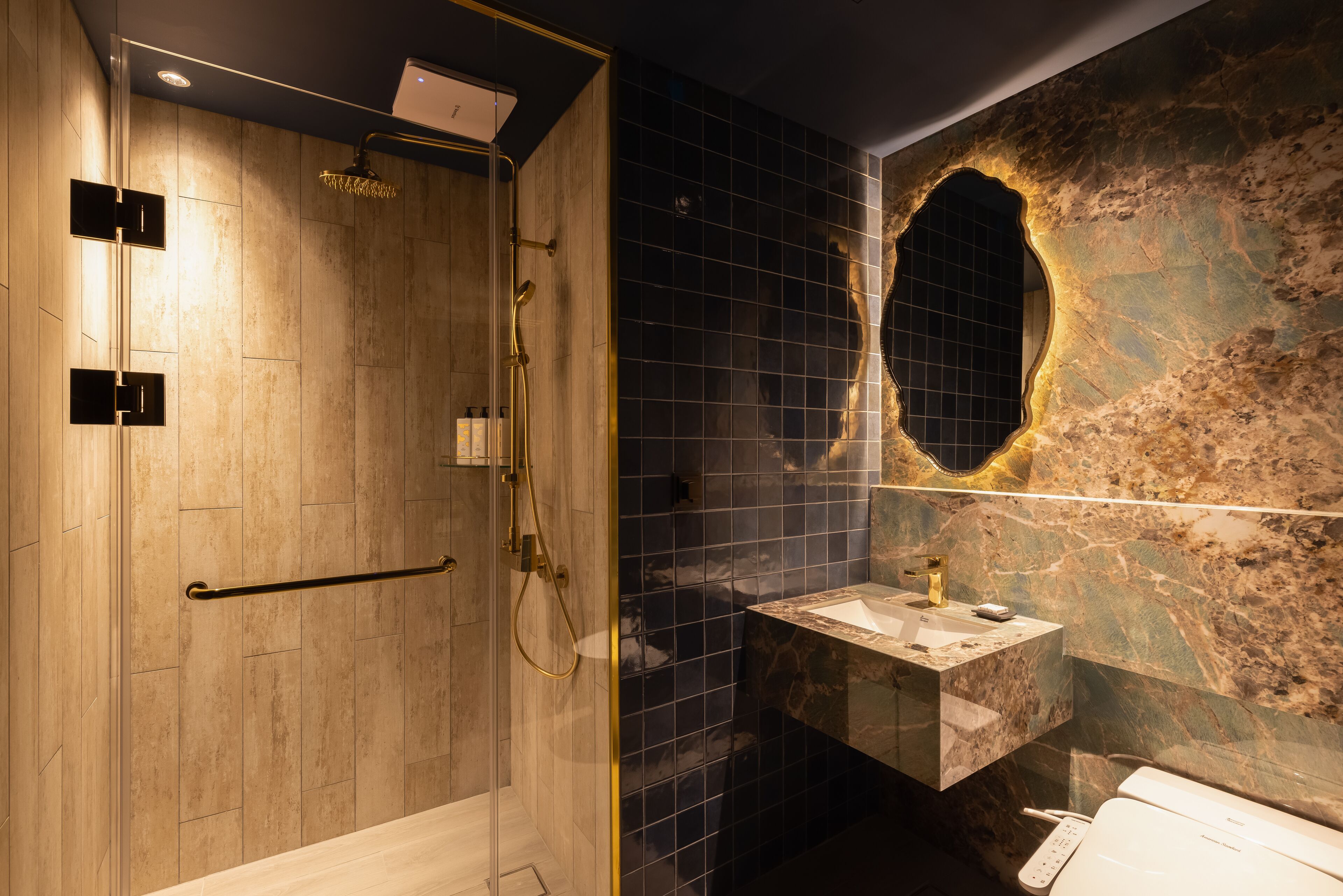 A modern bathroom with a glass-enclosed shower, a marble sink, and a unique wall design.