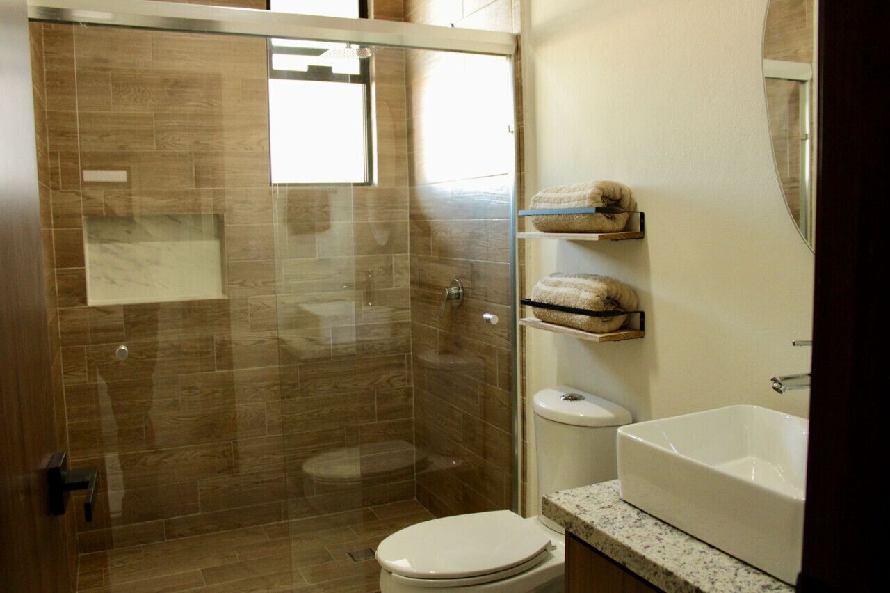 A bathroom with a glass-enclosed shower, a toilet, and a white bathtub.