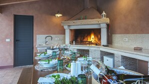 A dining area with a fireplace, wooden ceiling, and a table set for a meal. - Villa Runka (Istria - Muntic) (Muntic)