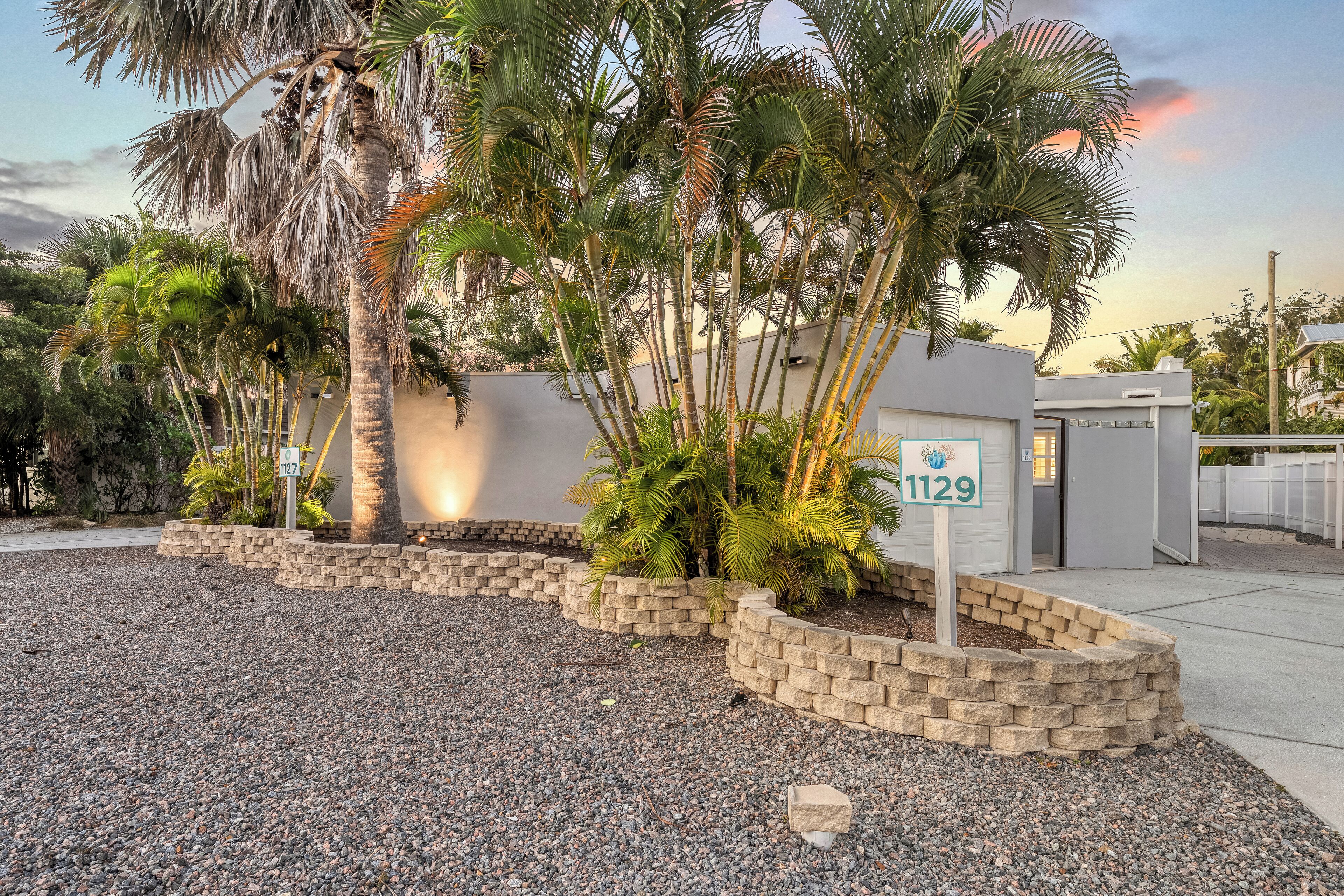 A residential property with a landscaped garden, a palm tree, and a mailbox with the number 1129.