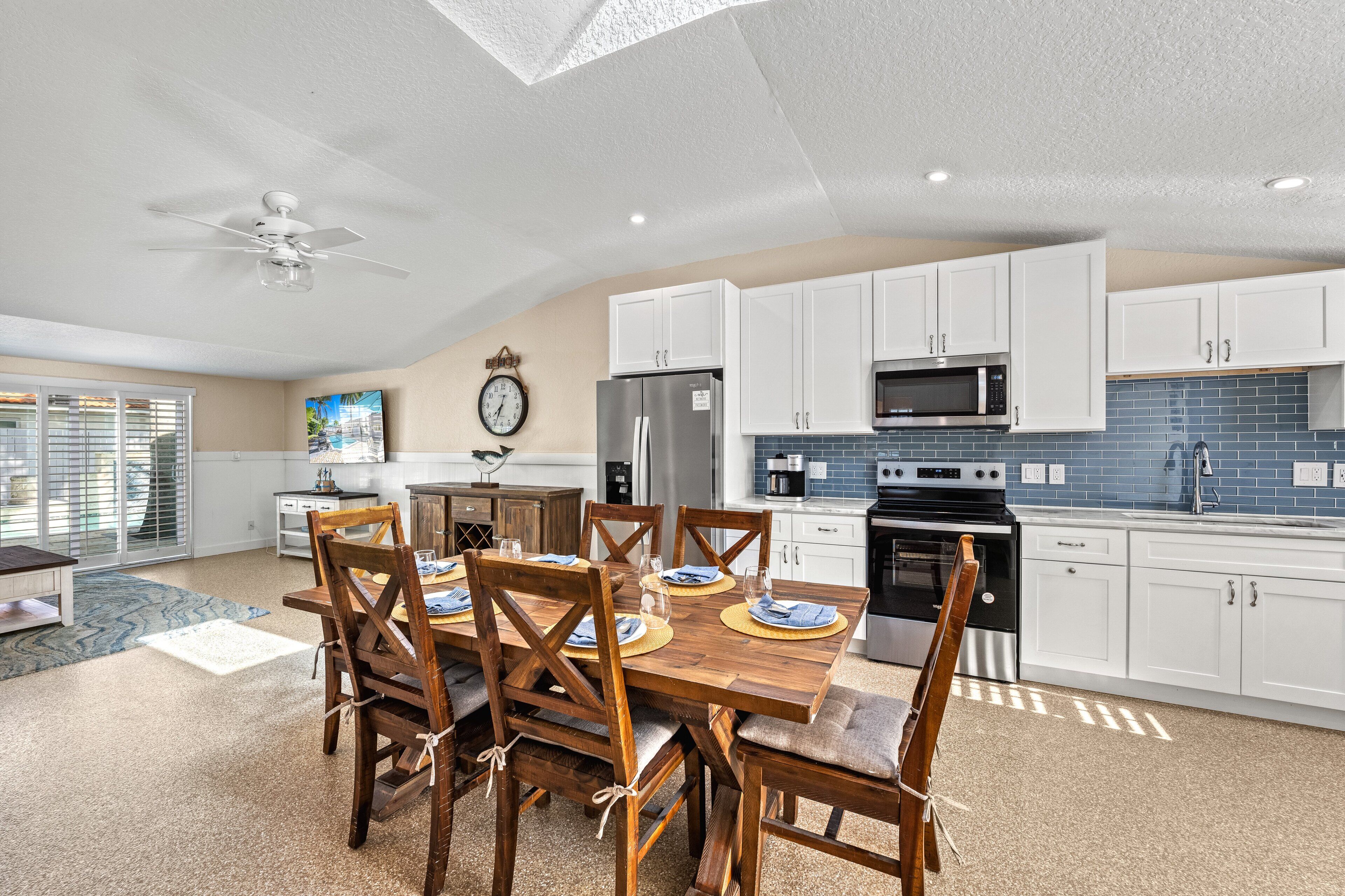 A modern kitchen with white cabinets, a stainless steel refrigerator, a microwave, and a stove.