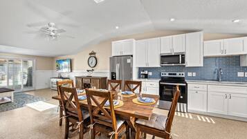 A modern kitchen with white cabinets, a stainless steel refrigerator, a microwave, and a stove.