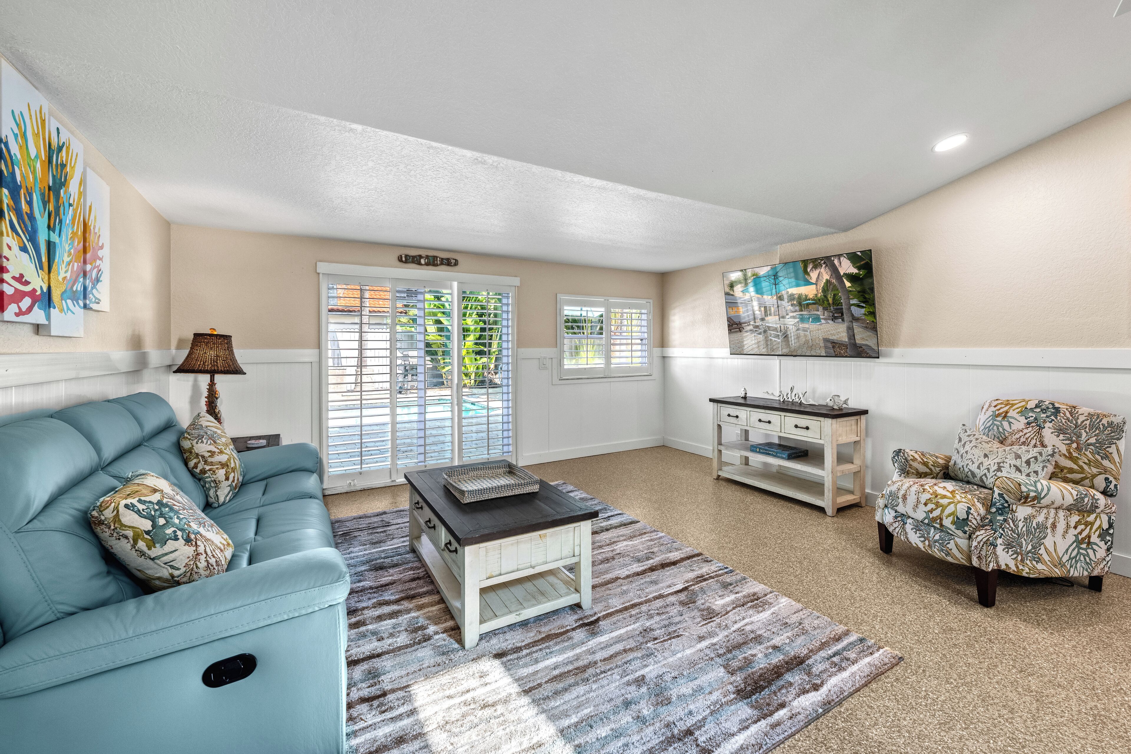 A living room with a blue sofa, a patterned armchair, a coffee table, and a painting on the wall.
