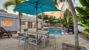 A patio with a pool, outdoor furniture, and a teal umbrella. - Key Life Reef l Semi-Private Pool, Walk to the Beach! (Siesta Key)