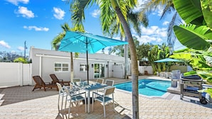 Ein Garten mit Pool, Terrassenmöbeln und Grill.