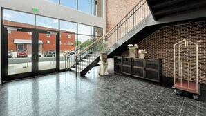 A spacious lobby with a staircase, large windows, and a brick wall. - 5 Minutes from I65 | In the heart of Cullman | Experience The Frankweiler (Cullman)