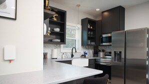 A modern kitchen with a marble countertop, stainless steel appliances, and dark cabinetry.